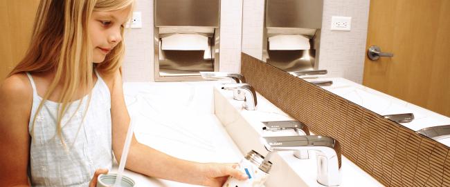 Girl filling water canister using Sloan faucet